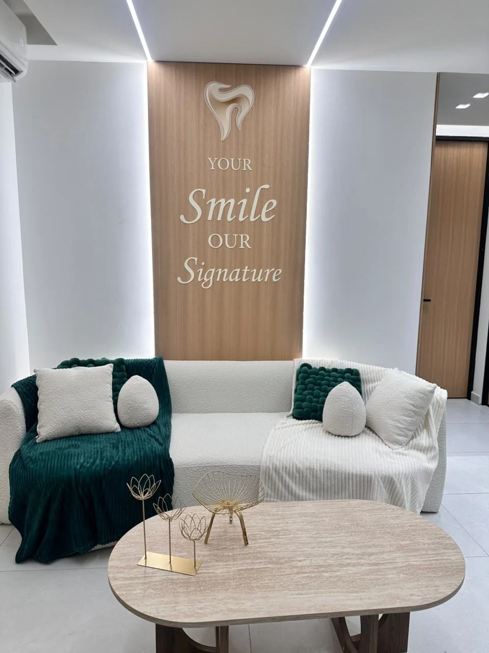 The clinic’s ivory lounge and emerald throws beneath the Signature Smile slogan