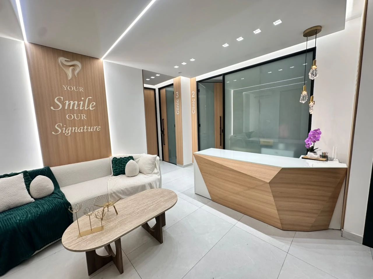Signature Smile reception in Zalka, with natural oak, ivory bouclé seating, emerald accents and warm architectural lighting